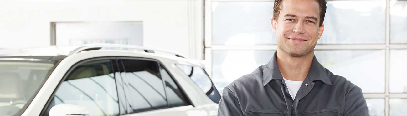 Mécanicien automobile debout dans un atelier devant un véhicule
